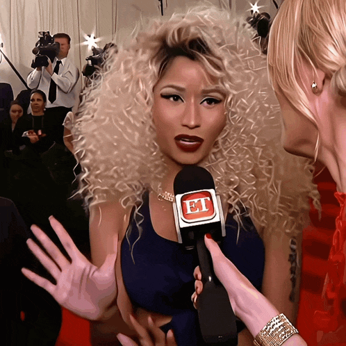 a woman with curly hair is being interviewed by a woman holding a microphone with the letter e on it