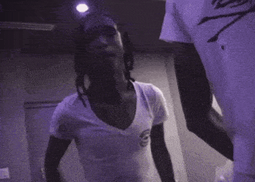 a man with dreadlocks is wearing a white t-shirt and making a peace sign