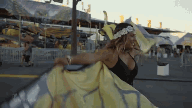 a woman in a black top is holding a yellow and gray flag that says ' a ' on it