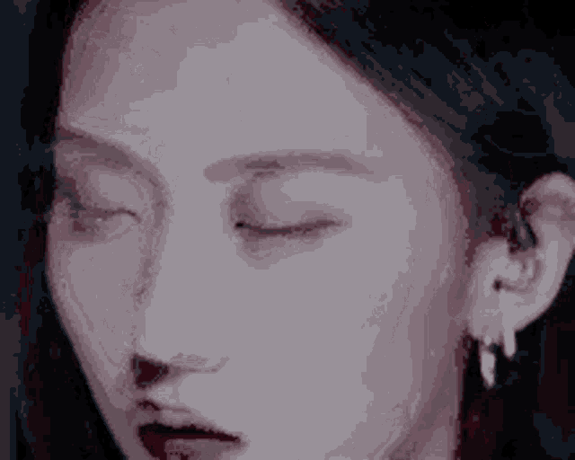 a close up of a woman 's face with her eyes closed and earring .