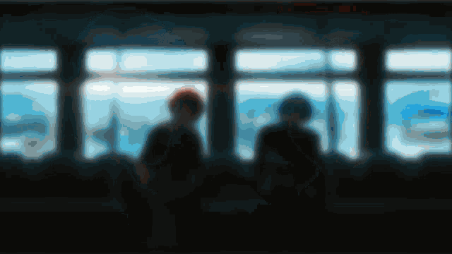 two people are standing in front of a window with a blue sky in the background