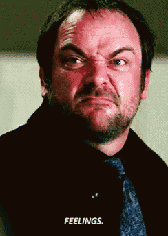 a man in a black shirt and tie is making a funny face with the words feelings written below him