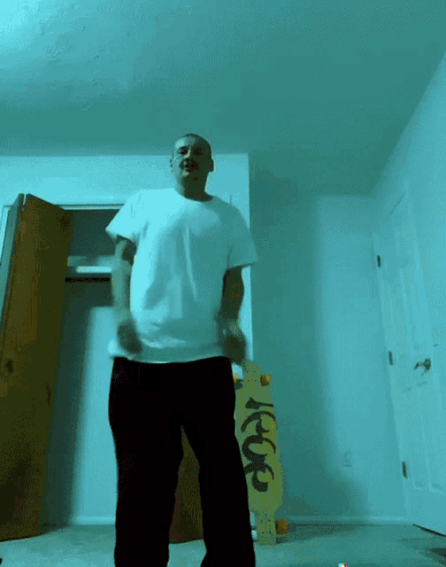 a man in a white shirt is dancing in front of a yellow skateboard that says ' ice ' on it