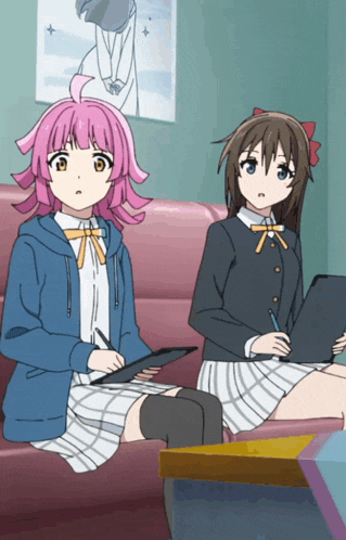 two anime girls are sitting on a couch one is holding a tablet