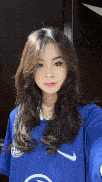 a woman wearing a blue nike shirt is taking a selfie