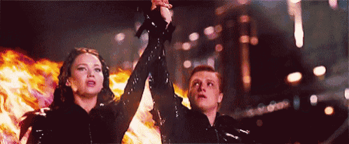 a man and a woman are holding hands in front of a fire in a dark room .