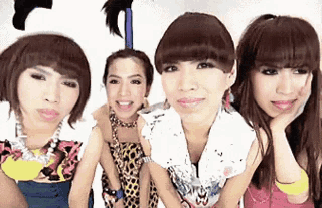four women are posing for a picture and one has a feather on her head