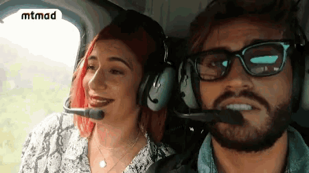 a man and a woman wearing headphones in a helicopter with the word mtmad on the bottom right