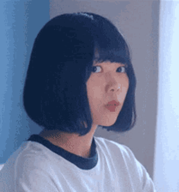 a woman with short black hair is wearing a white t-shirt with a black collar .
