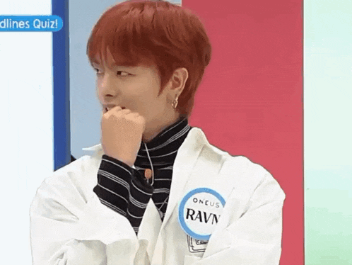 a young man with red hair is wearing a white jacket and a name tag on his shirt .