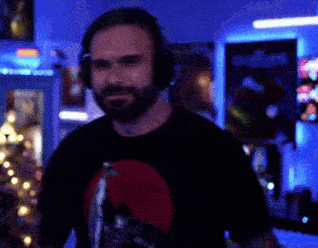 a man with a beard wearing headphones stands in a dark room