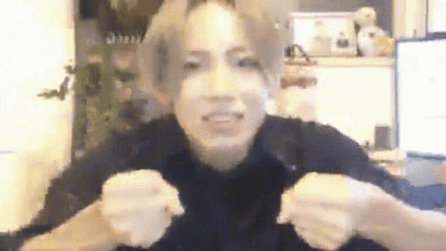 a blurry picture of a person making a funny face with their hands in the air .