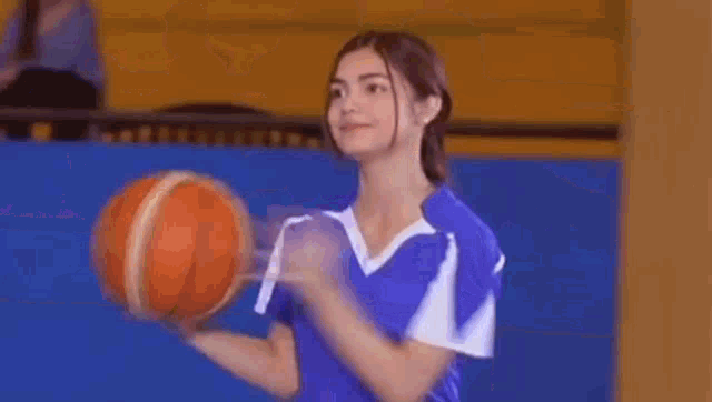 a man in a blue and white striped shirt is standing in front of a basketball .