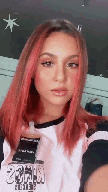 a woman with red hair is taking a selfie with her cell phone .