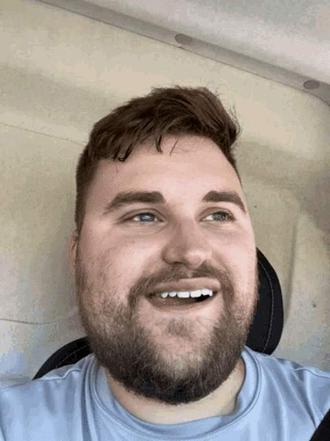 a man with a beard wearing a blue shirt is smiling