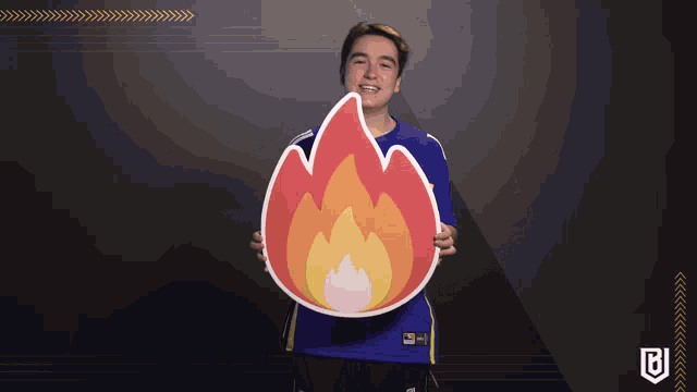 a man in a blue shirt is holding a cardboard fire icon