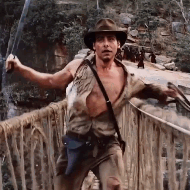 a man in a cowboy hat is walking across a bridge
