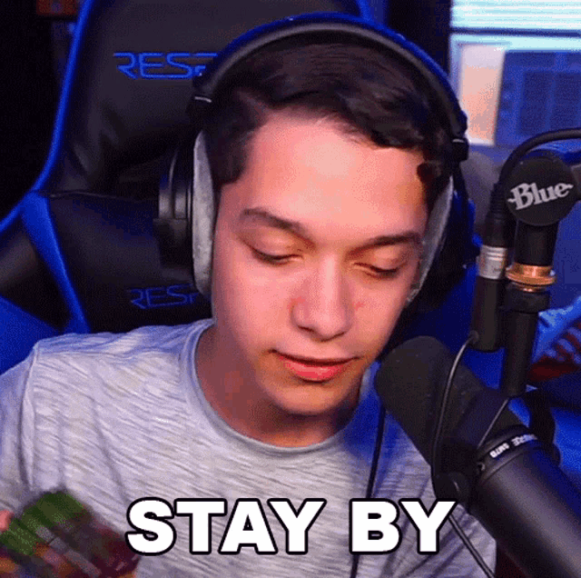 a man wearing headphones and holding a cube says stay by