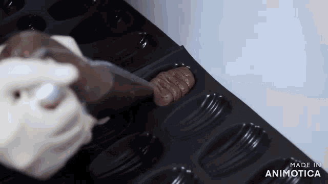 a person is pouring chocolate into a pan that says made in animatica on the bottom