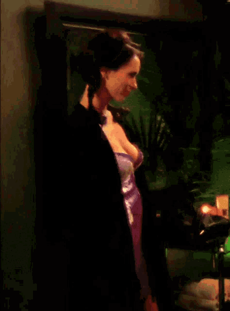 a woman in a purple dress is standing in front of a mirror