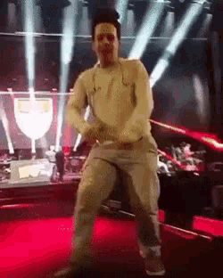 a man is dancing on a stage with a trophy in the background