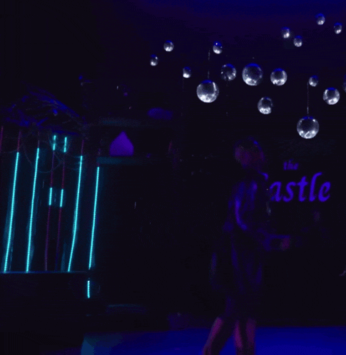 a man is walking in a dark room with purple lights