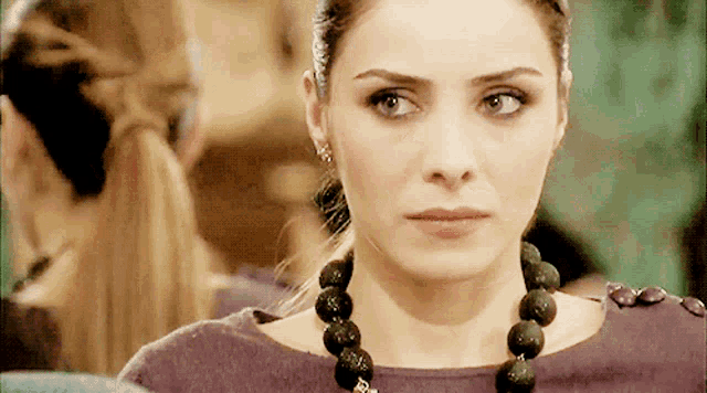 a woman wearing a purple top and a black necklace