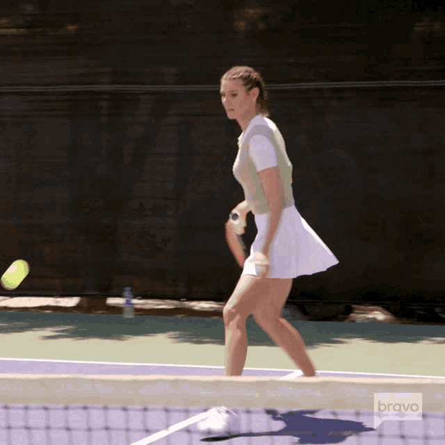 a woman is playing tennis on a court with the bravo logo in the background