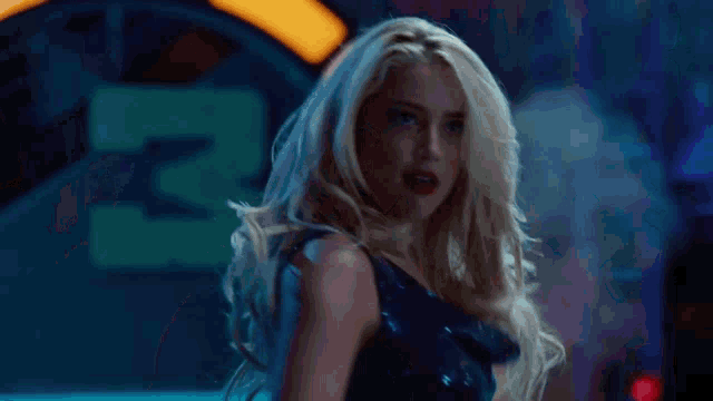 a blonde woman in a blue dress is standing in front of a sign that says 3