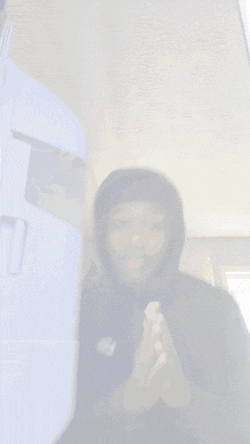 a man wearing a black nike hoodie stands in front of a white refrigerator