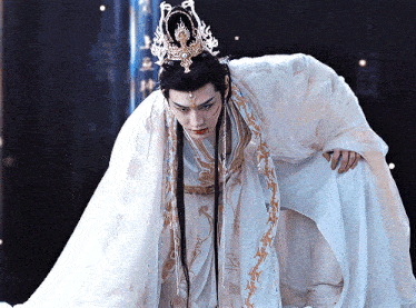a man wearing a crown and a long white gown