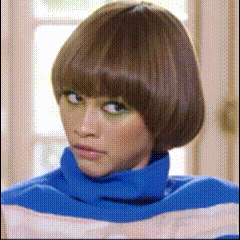 a woman wearing a blue and white striped turtleneck sweater looks at the camera