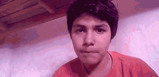 a young man in a red shirt is making a face .