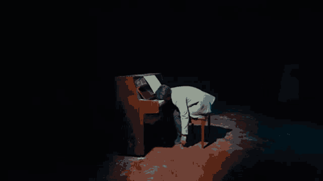 a man is kneeling down in front of a piano with a woman standing behind him