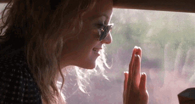 a woman wearing sunglasses looks out a window