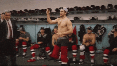 a shirtless hockey player is standing in a locker room