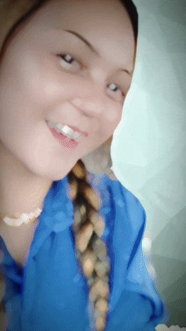 a woman wearing a blue shirt and a braided ponytail is smiling
