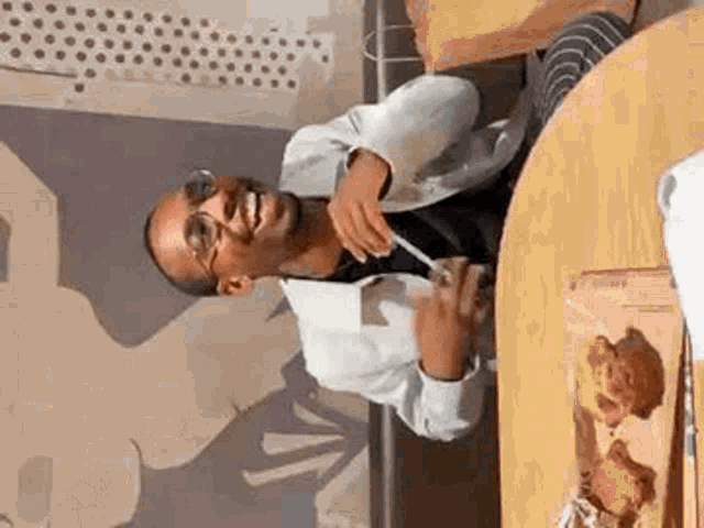 a man is sitting at a table with a straw in his mouth