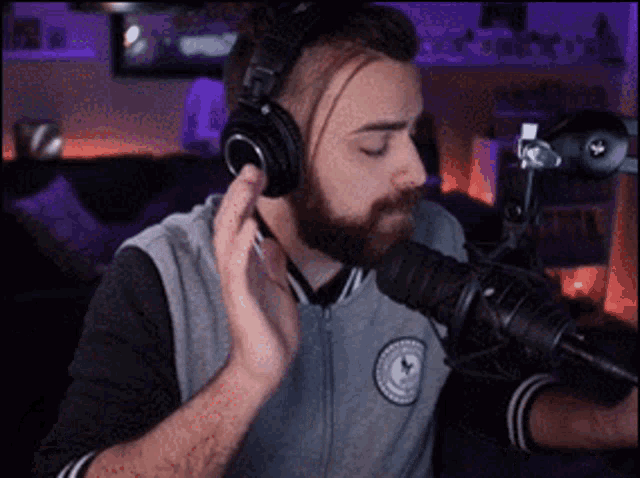 a man with a beard is wearing headphones and singing into a microphone