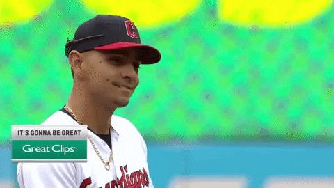 a man wearing a cleveland indians baseball uniform stands in front of a green background
