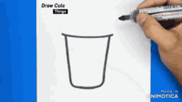 a person is drawing a cup with a marker on a blue background