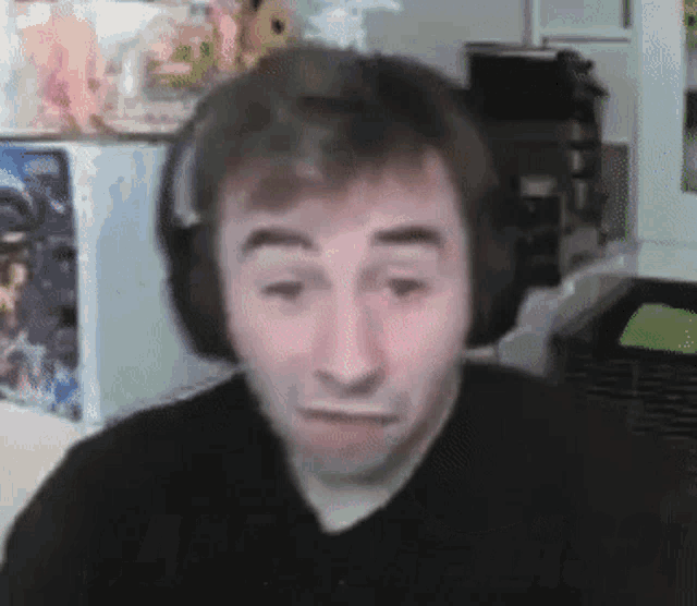 a man wearing headphones is making a funny face while sitting in front of a refrigerator .