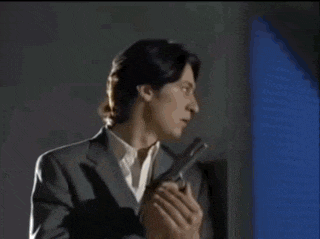 a man in a suit is holding a gun in his hand