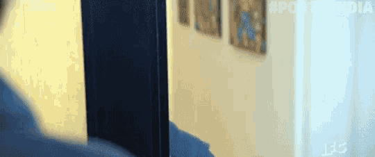 a person is standing in front of a door with a painting on the wall behind them .