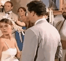 a bride and groom are standing in front of a crowd of people at a wedding reception .