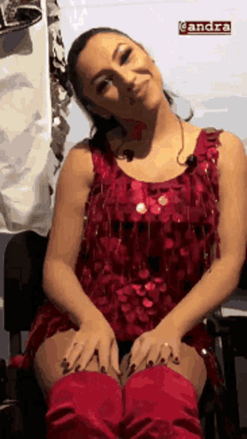 a woman in a red dress and red boots is sitting in a chair with her hands on her knees .