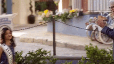 a man and a woman are standing next to each other on a sidewalk in front of a chain link fence .