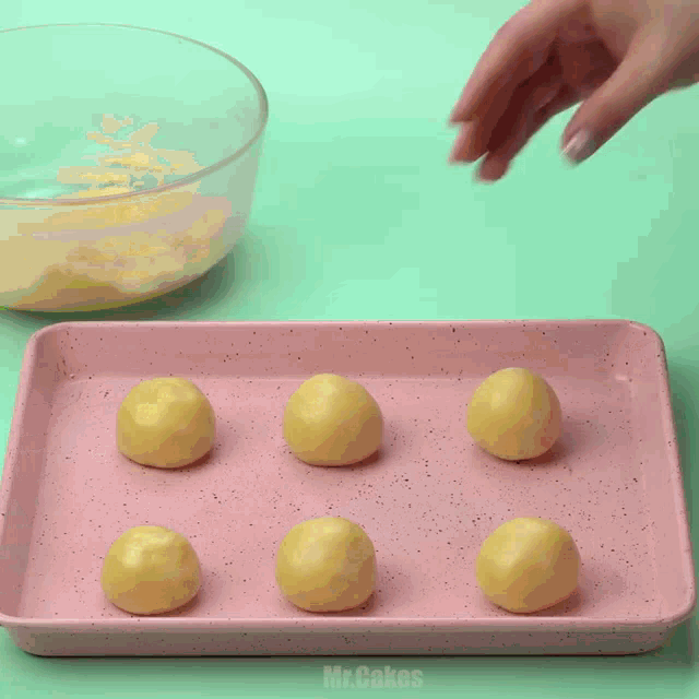 a pink tray with yellow balls on it that says mr cakes on the bottom