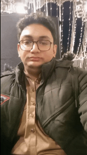 a young man wearing glasses and a black jacket takes a selfie