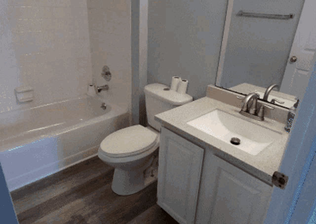 a bathroom with a toilet a sink a tub and a mirror